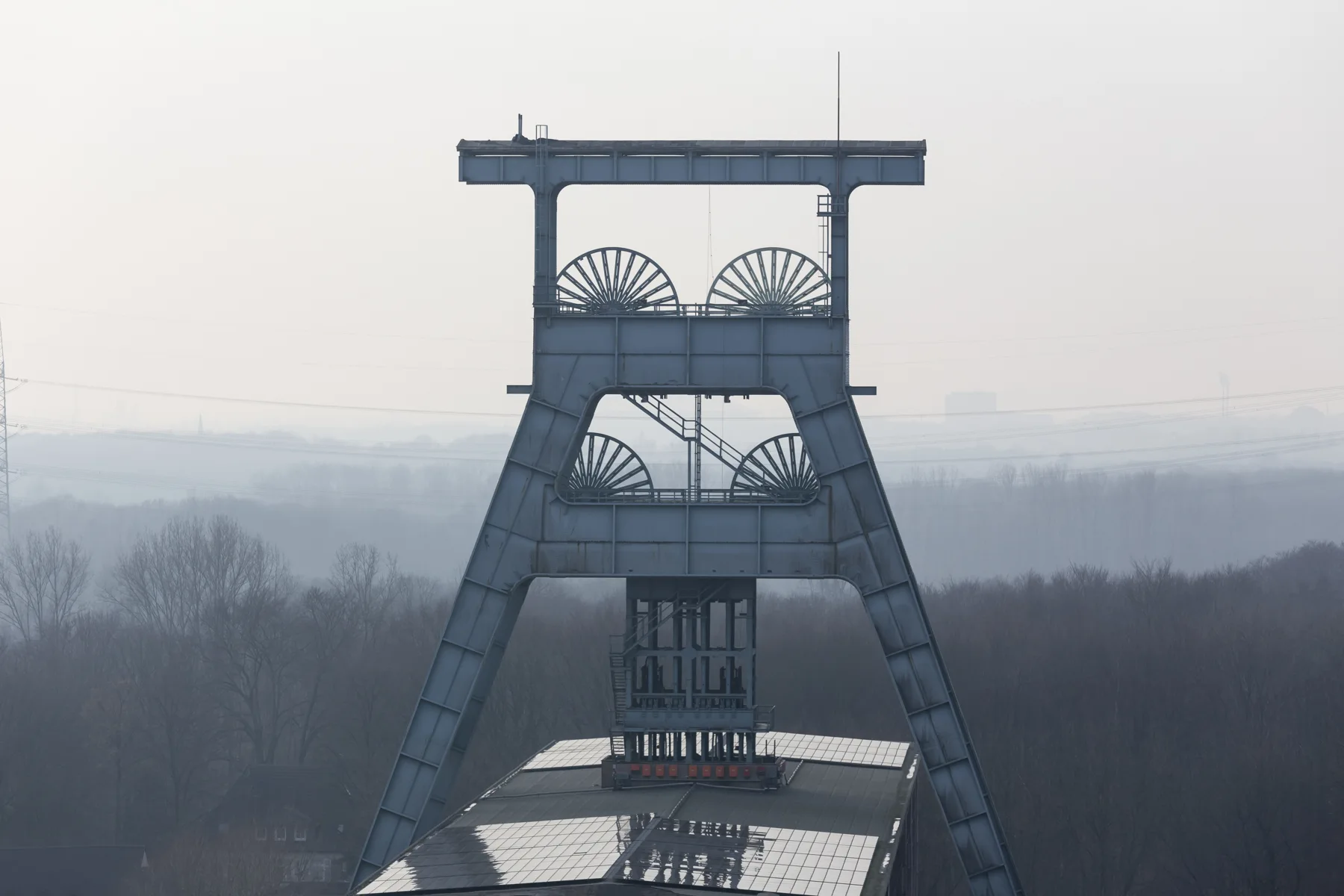 Illustrative mine headgear rising above a misty landscape